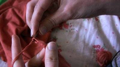 " A woman  crochet a  neckline of a dress "