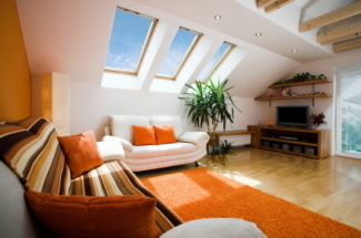 Furniture fills a room with skylights and wooden flooring.
