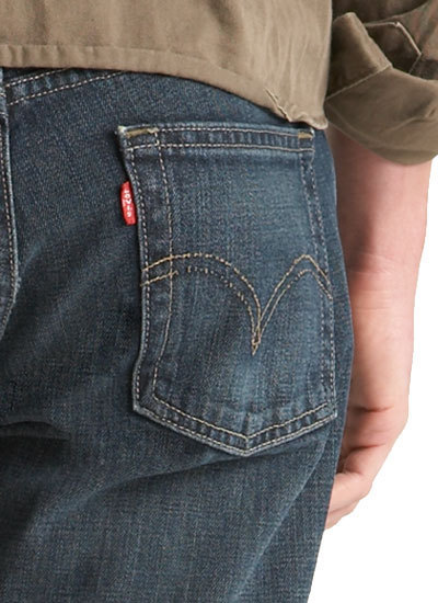 A red tag is on the side of a back pocket of a pair of jeans.