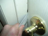A person is holding the gold colored knob of a white door.
