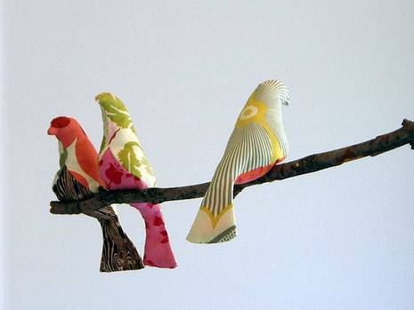 Three colorful dove statues on a branch.