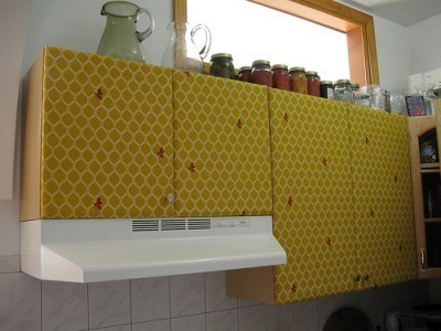 Yellow honeycombed cabinets over the hood of a stove.