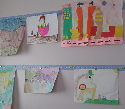 A wall with two rows of kids artwork.