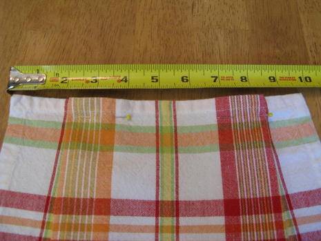 Measuring tape next to pink and white plaid fabric.
