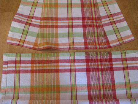 Two red and green plaid placements sit on a wooden table.