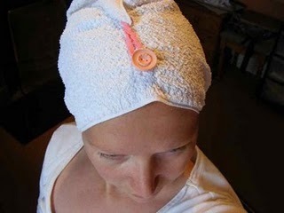 A woman wearing a turban made out of a towel, closed with a pink button.