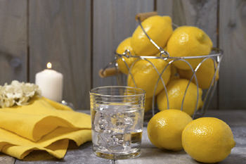 A handful of lemons with a glass and white candle