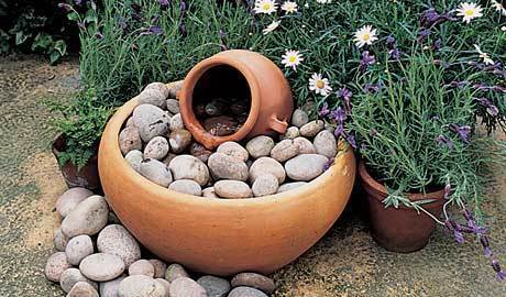 A series of pots with lavender in them, and one big one with rock in it.