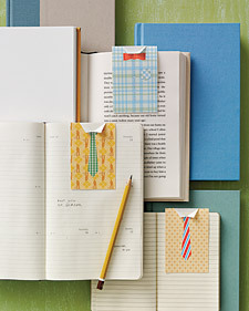 Several open books with bookmarks resembling 'shirt and tie' and a single pencil, sitting atop closed books.
