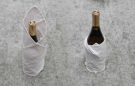 Demonstrating how to wrap a bottle of wine with napkins.