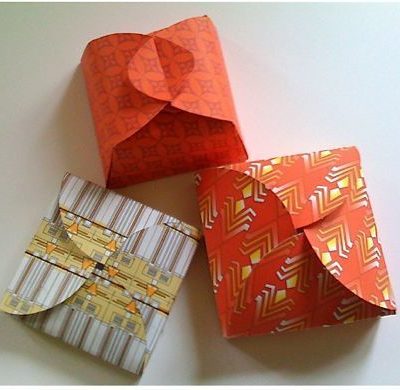 Three to-go boxes are closed with different paper folding techniques.