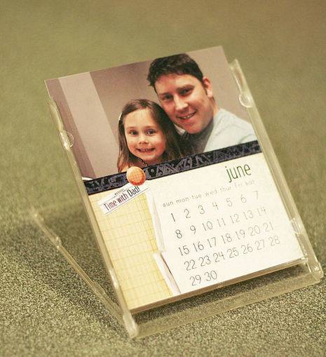 A calendar in a holder that is showing a dad and his daughter.