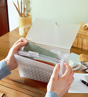 Two hands opening a small transparent cloth organizer on a tan desk.