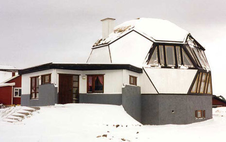 A home has an annex that is shaped like an orb with a chimney.