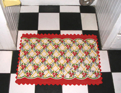 A red and green rug sits on a checkerboard floor.