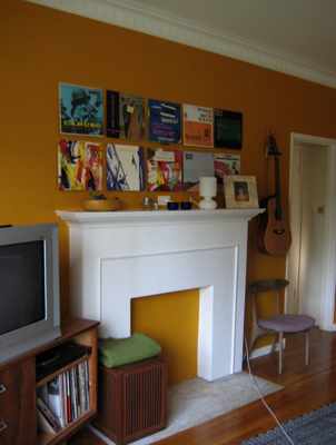 A blocked up fire place with many framed albums and a guitar near it.
