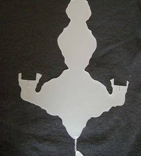 A white paper cutout of a chandelier sits on a black background.