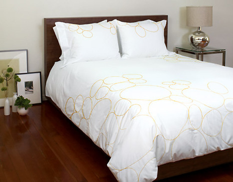 A bed covered in a white and gold bedspread.