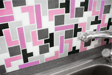 A kitchen sink, along with a black and pink tile background.