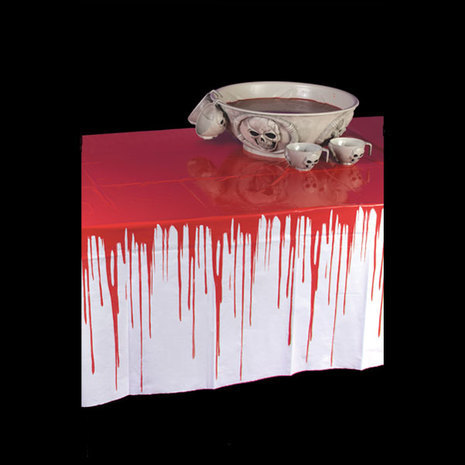 A white table cloth with fake blood on top with a punch bowl.