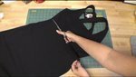 A girl cutting a black dress with scissors