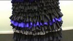 A black frilly dress that has a band of purple in the skirt.