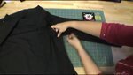 A woman sews a black shirt on a green crafting mat.