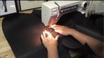 A series of leather flaps being sewed in a machine.