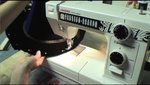 A black item being sewn on a machine.
