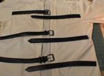 Six black belts lay on a white sheet.