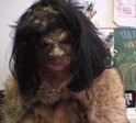 A person with a scary mask and large black wig on.