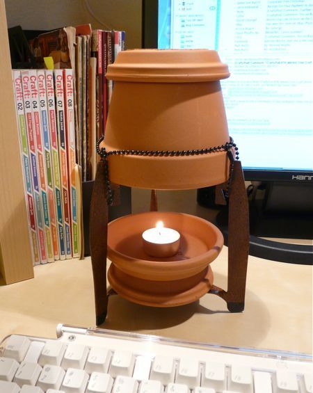 A terra cotta candle burner is sitting near some books.