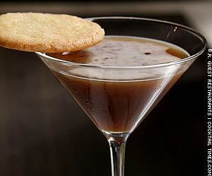 A martini glass with brown liquid and a sugar cooking resting on the edge.
