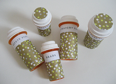 Empty prescription bottles decorated with green polka dots have been repurposed as holders for crafting supplies.