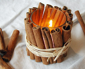 Candle holder surrounded by cinnamon sticks.