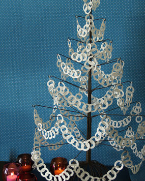 A Christmas tree made of paper in front of a blue wall.