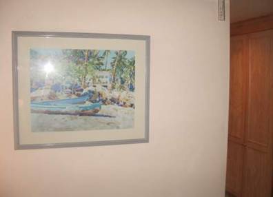 A painting of two blue kayaks on a sandy beach hanging on the wall.