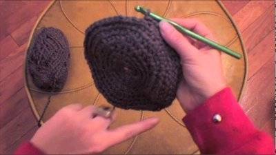 Two hands crocheting with black fabric.