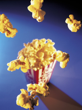 A box of popcorn with floating popcorn pieces.