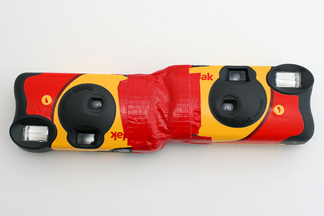 A pair of disposable cameras that have been taped together.