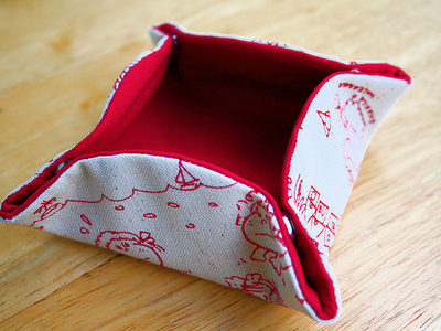 A container made of red fabric that snaps together to carry small objects.