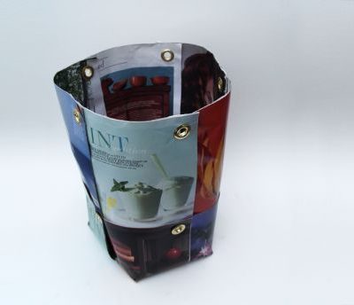 Magazine pictures shaped into a trash can with brass eyelets.