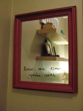 A framed mirror has cursive writing on it.