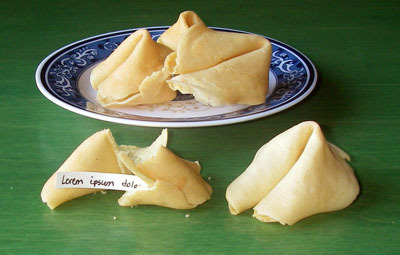 Homemade fortune cookies on a blue porcelain plate and green table.