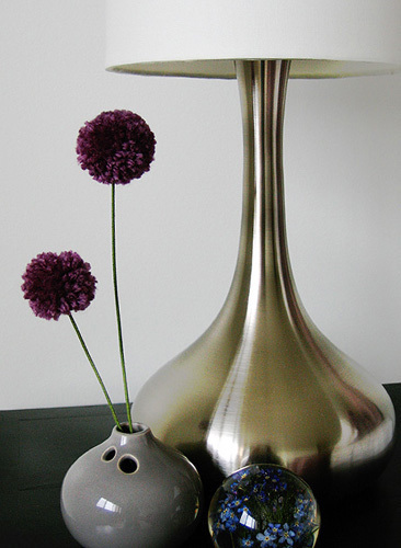 A gold lamp next to skinny flowers.