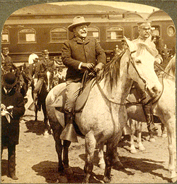 A man on a horse is in front of other horse riders and a train.