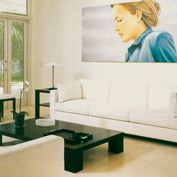 A clean minimalist modern room with a picture of a housekeeper over top of the main sofa.