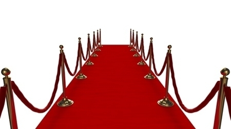 Red velvet ropes are on top of a red carpet.