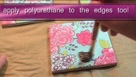 A paint brush is brushing a book that has purple and pink flowers painted on a baby blue background.