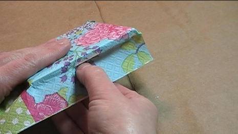A man pushes a colorful napkin over a piece of tile.